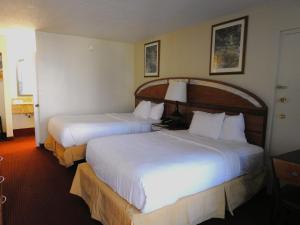 a hotel room with two beds with white sheets at Quality Inn Orlando-Near Universal Blvd in Orlando