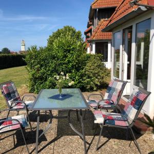 a patio table with chairs and a vase of flowers at Ferienwohnung-Feldblick in Petersdorf auf Fehmarn
