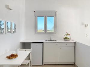 a white kitchen with a sink and a table at Palm Suite Green in Porto Heli