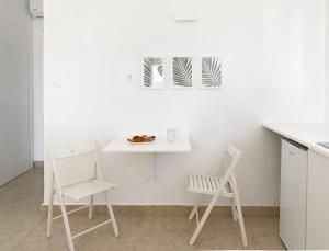 a table and two chairs in a white kitchen at Palm Suite Green in Porto Heli