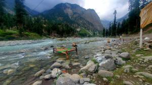 a river with rocks and a boat in the middle at Anakar resort in Kalām +9 photos