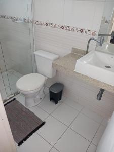 een witte badkamer met een toilet en een wastafel bij Casa praia Itanhaem c piscina in Itanhaém