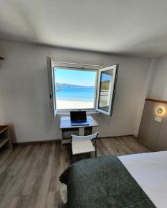 1 dormitorio con escritorio y ventana con ordenador portátil en Nemiña Alojamiento turístico, en Nemiña