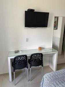a desk with two chairs and a television on a wall at O paraíso em um flat à beira-mar de Carneiros in Tamandaré