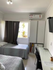 a bedroom with two beds and a desk and a window at O paraíso em um flat à beira-mar de Carneiros in Tamandaré +8 photos