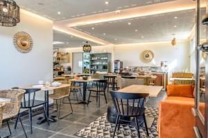 a restaurant with tables and chairs in a room at Hôtel Le Martray in Ars-en-Ré