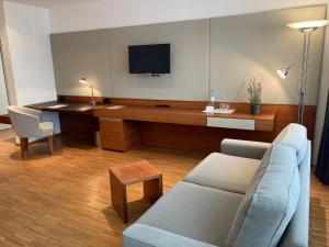 uma sala de estar com um sofá e uma secretária com uma televisão em Gästehaus an der Oase em Versmold