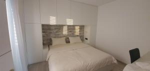 a small bedroom with a bed in a white room at Sunset holiday Krk in Linardići