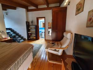 1 dormitorio con 1 cama, 1 silla y TV en Maison Di Gugli, en Brandizzo