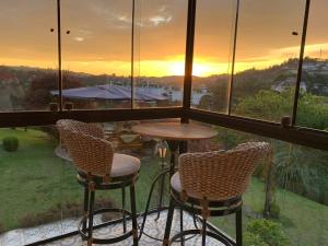a balcony with a table and chairs and a sunset at Casablanca Hotel Boutique in Campos do Jordão