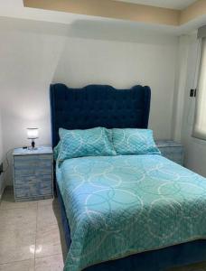 a bedroom with a blue bed and a night stand at Depa Frente al aeropuerto 8huespedes 103 in Mexico City