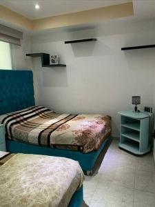 a bedroom with two beds and a table with a night stand at Depa Frente al aeropuerto 8huespedes 103 in Mexico City