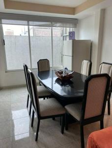 a dining room table with chairs and a kitchen with a refrigerator at Depa Frente al aeropuerto 8huespedes 103 in Mexico City