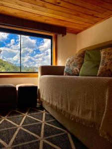 sala de estar con sofá y ventana grande en Tiny House Urubici en Urubici