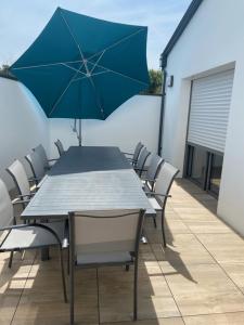 een tafel en stoelen met een blauwe parasol op een patio bij Les Villas du Fief in Jard-sur-Mer