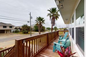 a porch with blue chairs and palm trees on a house at Mermaid Tales in Dauphin Island