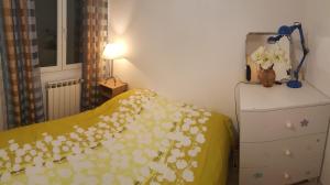 - une chambre avec un lit et une couverture jaune fleurie dans l'établissement Cosy Room in the centre, à Saint-Laurent-du-Var
