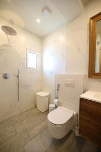 een witte badkamer met toilet en douche bij On the Beach (literally) stylish apartment with free P in Vlorë +27 foto's