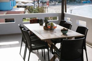 una mesa de madera con 2 copas de vino en el balcón en Beach front apartment with swimming pool, en Ligaria