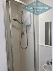 um chuveiro numa casa de banho com uma placa que diz casa de compressão tranquila em Gumfreston Guest House em Tenby
