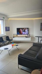 een woonkamer met een flatscreen-tv aan de muur bij frontaal gelijkvloers seaview 80m² 2 slp in Oostende