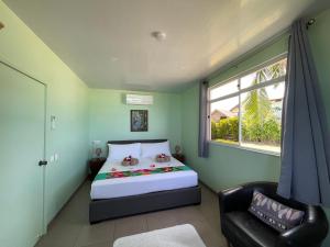 a bedroom with a bed and a chair and a window at Matira Beach Bungalow Waterfront in Bora Bora