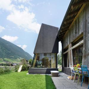 a house with a black roof with a table and chairs at Stadlnest Moser in Neustift im Stubaital