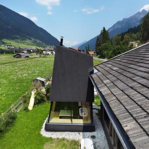 a house with a black roof on top of a field at Stadlnest Moser in Neustift im Stubaital