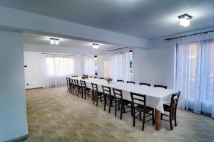 una grande sala da pranzo con un lungo tavolo e sedie di Pensiunea Farmecul Naturii și căsuțe individuale de închiriat Colibița a Colibiţa