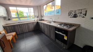 uma pequena cozinha com um fogão e um lavatório em Tauko tu casa em Paipa