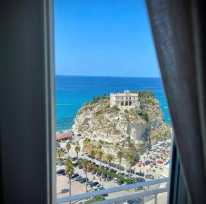 Blick aus einem Fenster auf einen Strand mit einem Schloss in der Unterkunft Sunset Tropea in Tropea