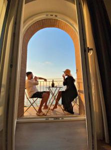 Ein Mann und eine Frau, die auf einem Balkon auf Stühlen sitzen in der Unterkunft Sunset Tropea in Tropea
