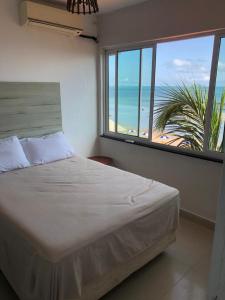 a bedroom with a bed and a view of the beach at Apartamento Vista Magnífica frente ao mar in Luis Correia