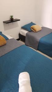 a room with three beds with blue and gray at VACACIONES a 3 km del Parque del Cafe in Montenegro