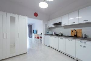 a white kitchen with white cabinets and a table at Luxury in City -3- Studio Bright & Secure Free Parking in Łódź +5 photos