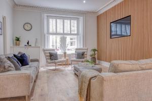 a living room with two couches and a tv at Andrean House, St Andrews in St Andrews