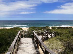 a wooden path to the beach with the ocean at Penelope Selfcatering Apartment in Wilderness