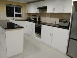 a kitchen with white cabinets and black appliances at Jacmo Guest Private Rooms in Cape Town