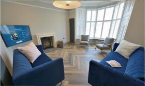 ein Wohnzimmer mit 2 blauen Sofas und einem Kamin in der Unterkunft 5 star luxury villa with Garden SPA in St Andrews