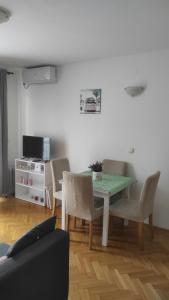salon ze stołem, krzesłami i telewizorem w obiekcie Apartment Simona w mieście Vrnjačka Banja