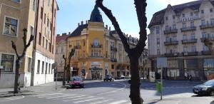 una calle de la ciudad con un edificio amarillo con una torre de reloj en Széll 3 Apartman, en Szombathely