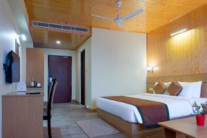 1 dormitorio con cama, escritorio y mesa en Treenz Hotel en Gangtok