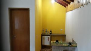 a room with a yellow wall and a kitchen with a counter at CHALES Canto dos Pássaros in Monte Verde +86 photos