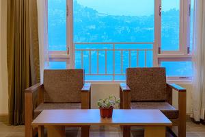 a room with two chairs and a table and a balcony at Treenz Hotel in Gangtok
