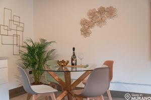 MURANO Place - RIVA House في مورانو: طاولة غرفة طعام مع كرسيين وزجاجة من النبيذ