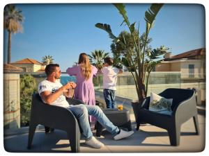 a man sitting in a chair on a patio with a family at Le Vallaya Suites & Spa in Menton