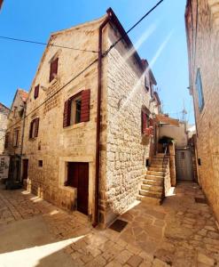 stary kamienny budynek z klatką schodową obok niego w obiekcie HVAR HEART HERITAGE STONE HOUSE 2 floors, up to 6 persons w mieście Stari Grad