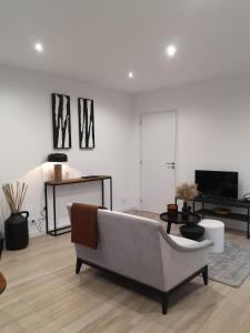 ein Wohnzimmer mit einem Sofa und einem Tisch in der Unterkunft Studio - Le Clos du fond cailloux in Longuenesse