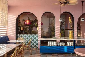 un restaurante con paredes rosas, mesas y espejos en Hotel Rocas de Bahía, en Bahía Inglesa