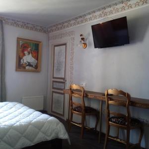 a bedroom with two chairs and a desk with a television on the wall at Appartement de Ville Médiévale in Vinça